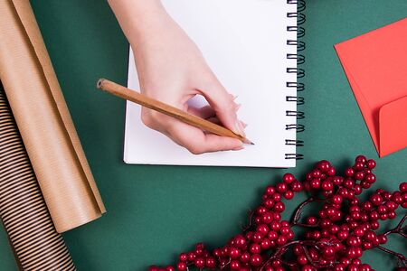 A girl is writing in a notebook with clean pages. Christmas decor. Planning concept.の写真素材