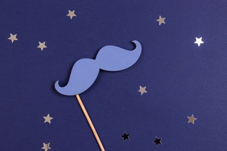 Blue fake mustache with sprinkling stars on a dark blue background. Flat lay.の写真素材