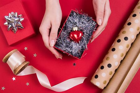 Red glass hearts in a red box with silver decor, beige ribbon, design papper. Top view. Holidays concept.の写真素材