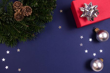 Red gift box, Christmas tree wreath, sprinkling stars, Christmas ball on a dark blue background. Holidays concept.の写真素材