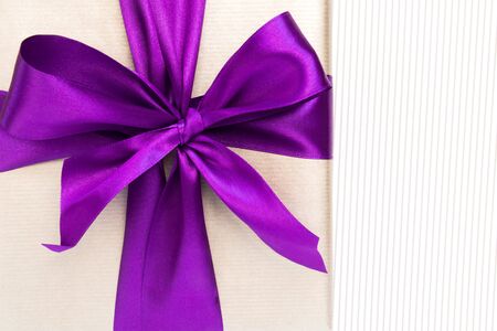 Vertical gift with violet ribbon and bow-knot on light background. Copy space.の写真素材