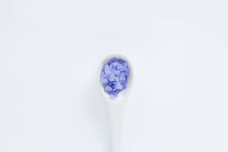 White decorative spoon with violet sea salts on the white background. Relaxing concept.の写真素材