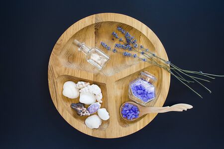 Seshels,violet seasalt, seastones, decorative bottles on the wooden round form on the black background. Top view. Spa and relaxing image.の写真素材