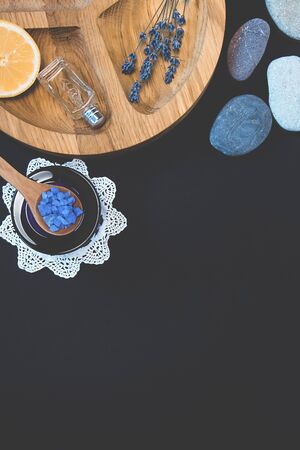 Seshels, lavender seasalt, seastones, decorative bottles, lemon on the wooden round form on the black background. Copy space. Spa and relaxing image.の写真素材