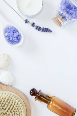 Flowers of lavender, white soap, candle, decorative bottles, brush for massage, sea salts, seashells on the white background. Relaxing concept.の写真素材