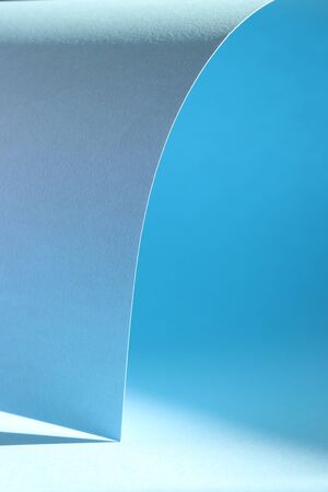 Pastel blue background with lights and shadows. Beautiful blue background with rolled-up paper. Shadow, light, geometric. Trend background.の写真素材