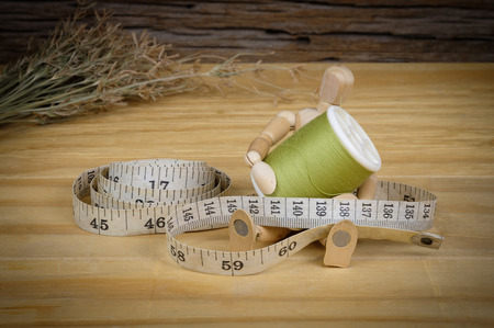 Sewing Supplies on Wood Background,Tape measure wrapped around a reel.の写真素材