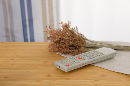 The remote control is placed on a wooden table with the morning sun. Warm moments and enjoyの写真素材