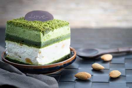 Macadamia cake with greentea and white cream on wooden table, close up, space to write.の写真素材