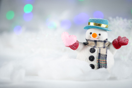 A snowman and mini heart pillow on bokeh background, with copy space for season greeting. Merry Christmas or Happy New Year, AF point selection.の写真素材