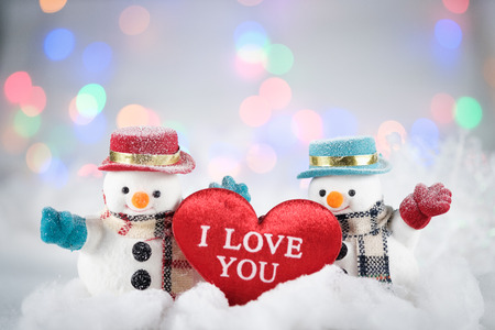 A snowman and mini heart pillow on bokeh background, with copy space for season greeting. Merry Christmas or Happy New Year, AF point selection.の写真素材