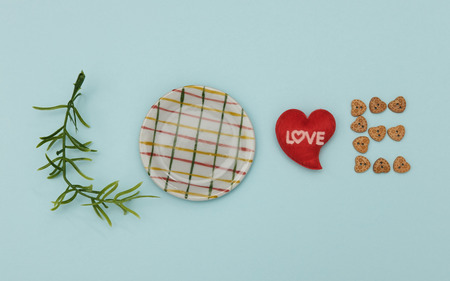 Words of love from leaves, dish, mini heart shape and wooden button on blue background, Valentine concept.の写真素材