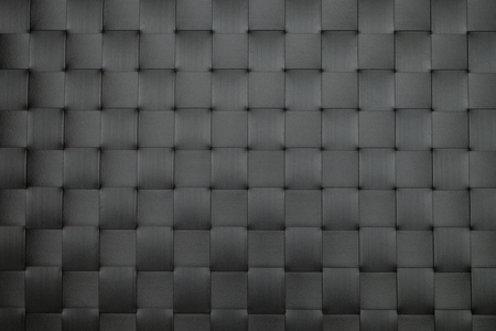 Close-up fragment of a black plastic wicker table mat as a backdrop texture