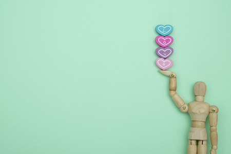 Wooden dummy holding a heart-shaped  on green background with copy space for write and valentine concept.の写真素材