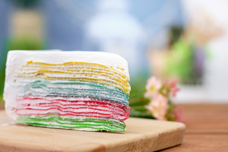 Rainbow crape cake on wooden plate. (Selective Focus)