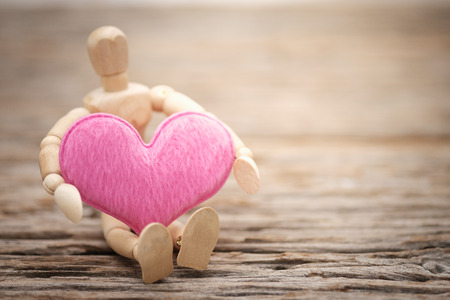 Pink pillow heart shape and wooden dummy with space to write. Valentine concept, Vintage tone, AF point selection.の写真素材