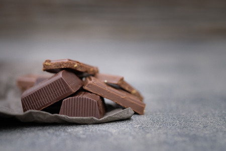 Broken chocolate bar placed on tables gray in low key light, Selective focus.の写真素材