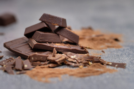 Broken chocolate bar placed on tables gray in low key light, Selective focus.