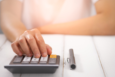 Businesswoman using a calculator on desk, Choose focus point. In over light.の写真素材