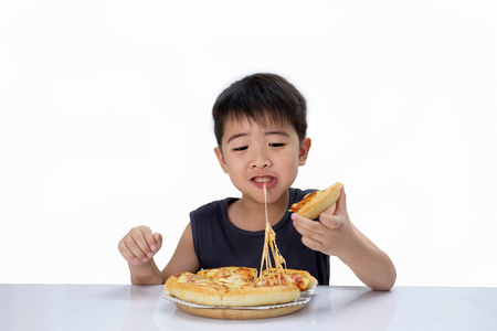 Asian boy is happy to eat pizza with a hot cheese melt stretched on a wooden pad.  Isolated over white.の写真素材