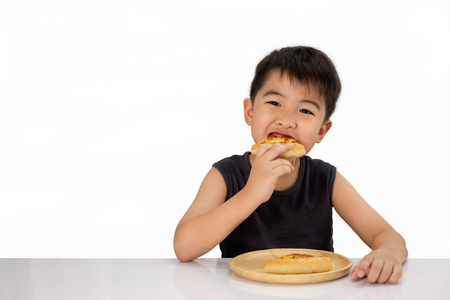 Asian boy is happy to eat pizza with a hot cheese melt stretched on a wooden pad on white background.の写真素材
