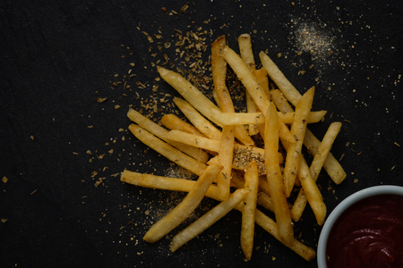 Fresh fried french fries with ketchup on black background. Choose focus point.の写真素材