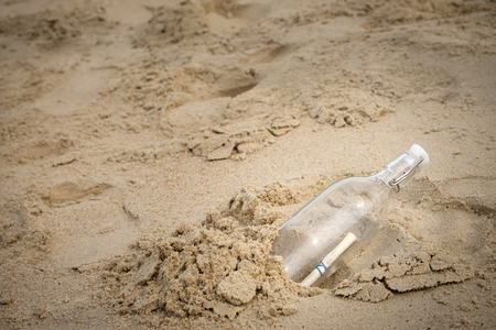Bottle with a message on the desert beach by the sea with copy space to write.の写真素材