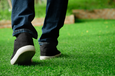 Black Sneakers shoes walking on green grass with copy space.の写真素材
