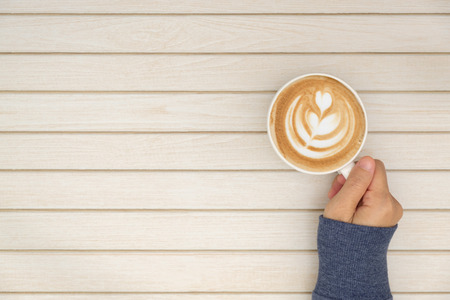 The woman's hand in sweater is holding a cup of coffee with copy space to write.の写真素材