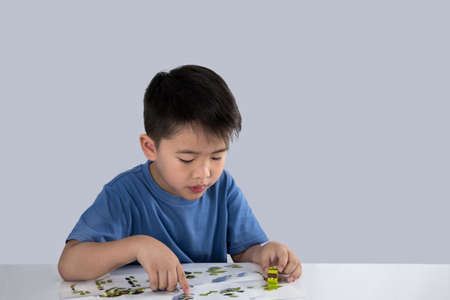 Portrait of cute asian boy playing with colorful plastic toy bricks at the table.