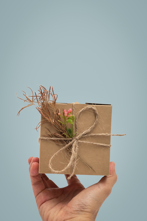 Hand holding a present, gift box rustic style on blue background.の写真素材