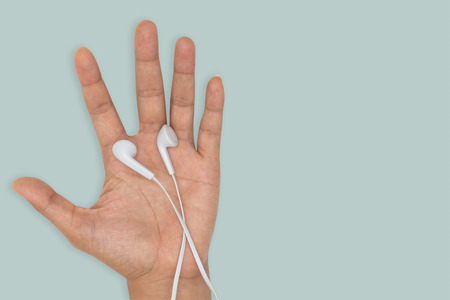 Top view-White headphones on human hand isolated on green background.