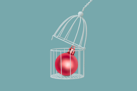 Christmas ball in bird cage isolated on blue background, minimal idea concept.の写真素材