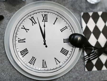 Dish with clock, black fork and spoon, Eating time concept.