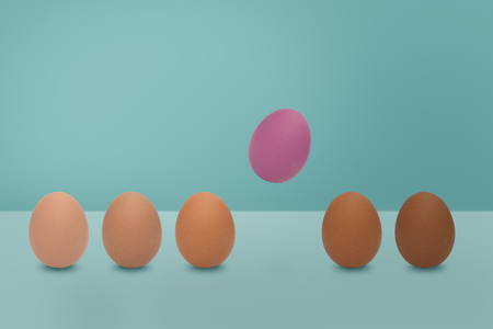 Flying pink egg and  different shades color of eggs on blue background. Minimal Easter idea concept.の写真素材