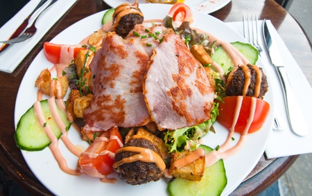 meatball, bacon and potatoes with lettuce on white platの写真素材