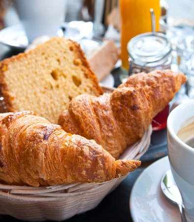 Breakfast with coffee and croissants in a basket on tableの写真素材