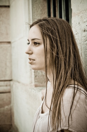 beautiful girl with long hair standing by white wallの写真素材