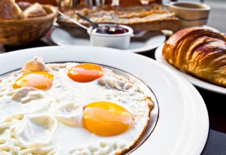 Breakfast with coffee and croissants in a basket on tableの写真素材