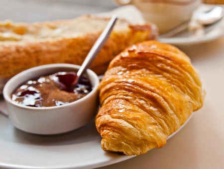 Breakfast with coffee and croissants in a basket on table