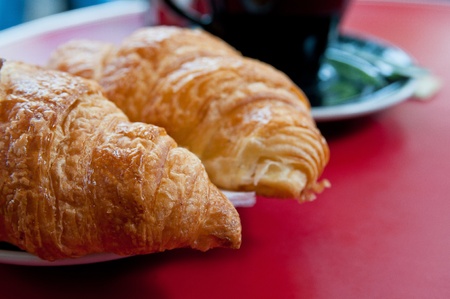 Breakfast with coffee and croissants in a basket on tableの写真素材