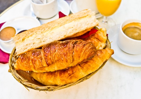 Breakfast with coffee and croissants in a basket on tableの写真素材