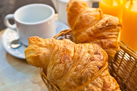 Breakfast with coffee and croissants in a basket on tableの写真素材