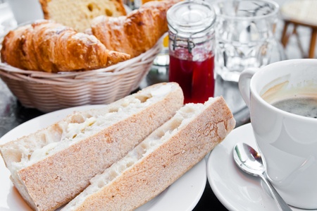 Breakfast with coffee and croissants in a basket on tableの写真素材