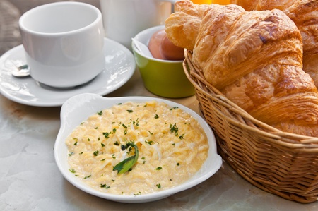 Breakfast with coffee and croissants in a basket on table
