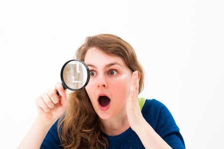 young woman through a magnifying glass with a surprised expressionの写真素材