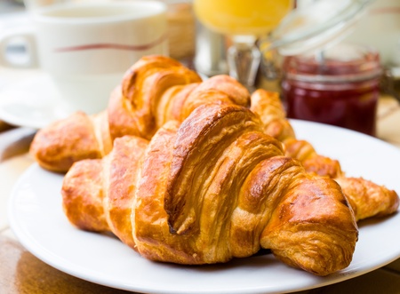 Breakfast with coffee and croissants in a basket on table