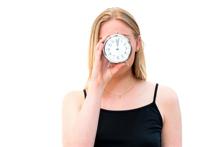 young beautiful woman holding a clock on a white backgroundの写真素材