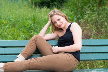 Beautiful young woman sitting on the bench in parkの写真素材