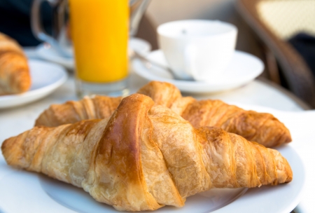Breakfast with coffee and croissants in a basket on tableの写真素材